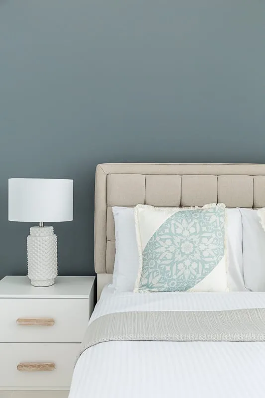 Un dormitorio con una cama bien tendida y una mesita de noche.