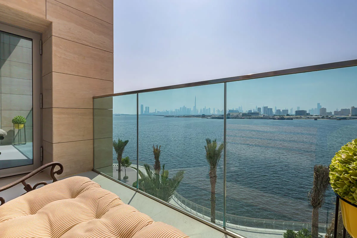 Una terraza junto al agua con asientos acolchados da a la costa y al horizonte lejano.