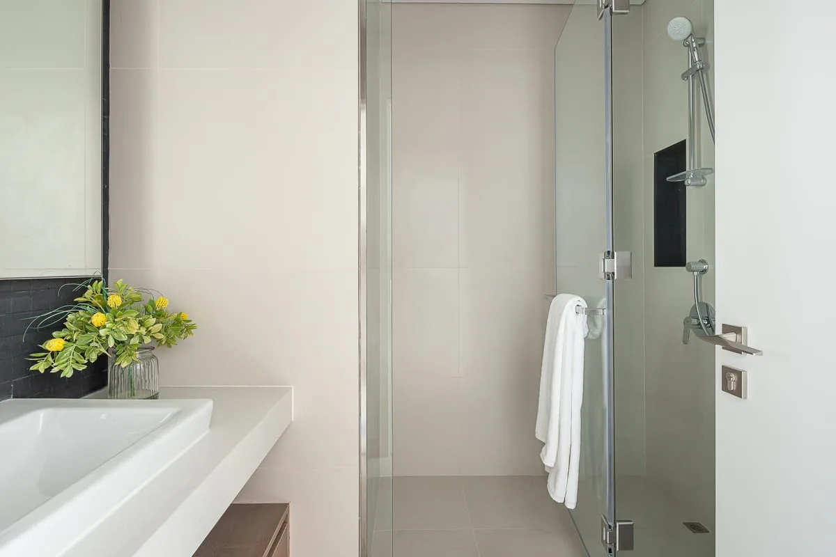 Un baño con bañera, ducha de cristal y una toalla.