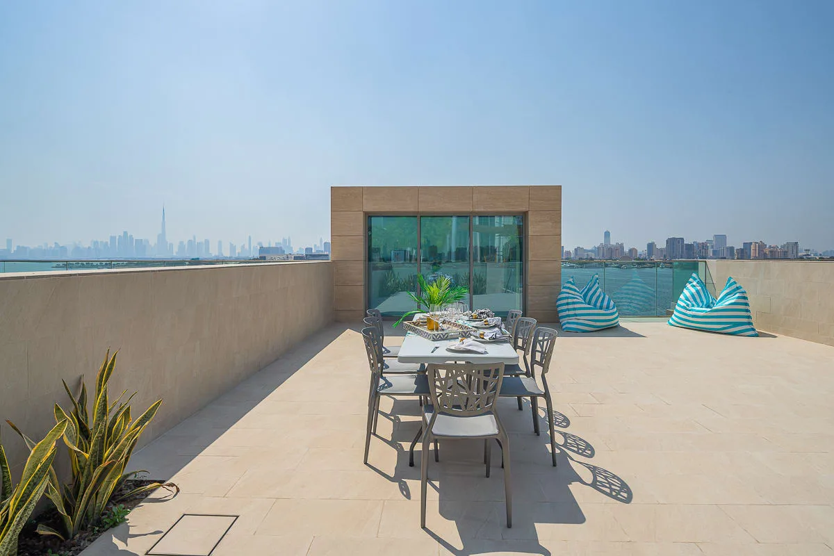 Una terraza en la azotea tiene una mesa al aire libre y asientos con rayas azules.