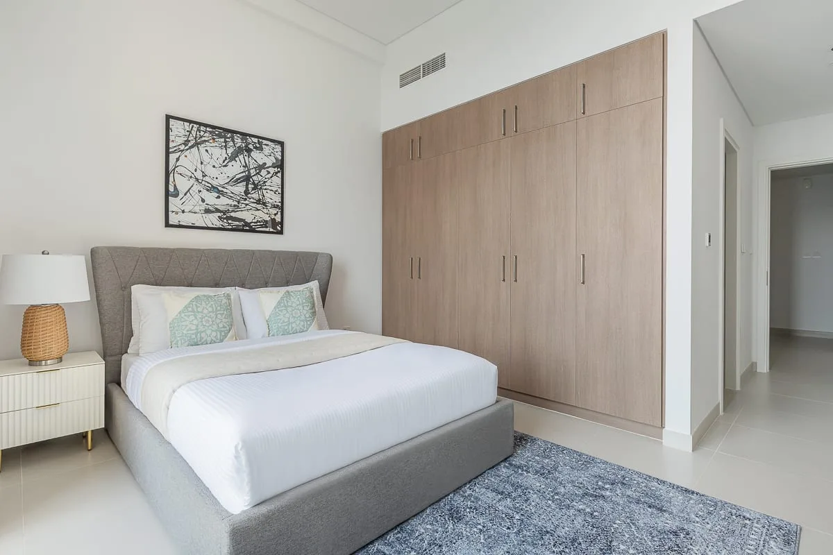 Un dormitorio con una cama, una mesita de noche y armarios empotrados.