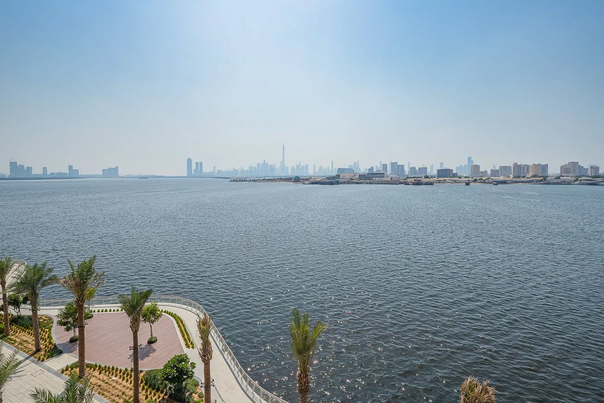Una amplia vista costera muestra agua abierta y un horizonte urbano distante.
