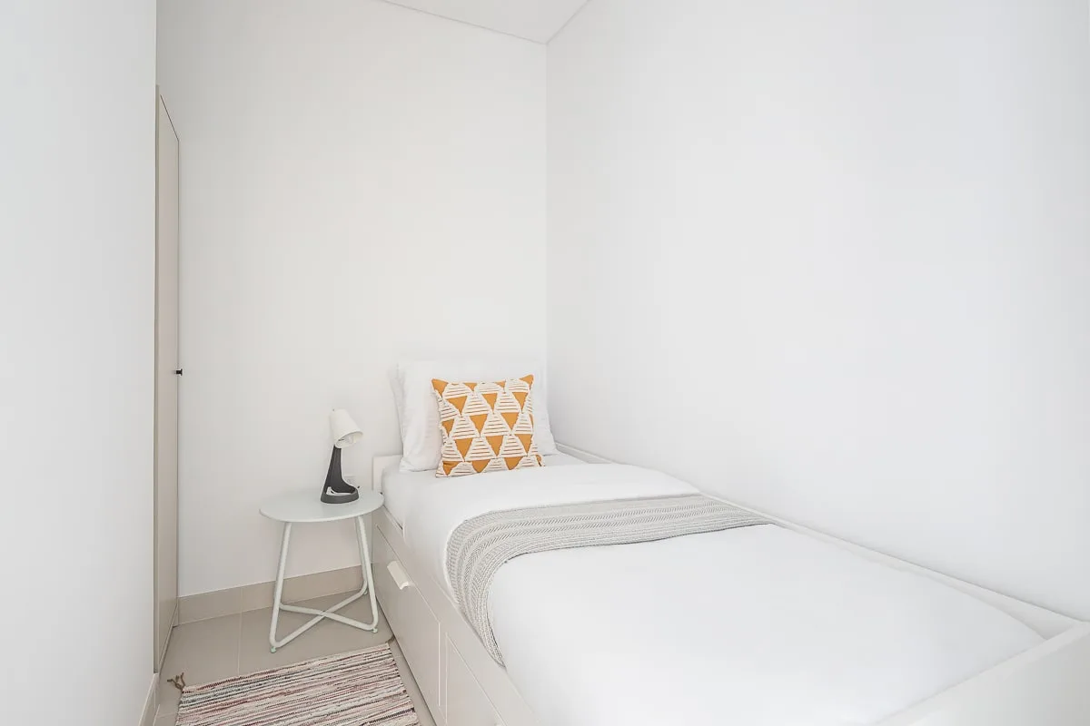 Un dormitorio luminoso con una cama individual y un cojín estampado.