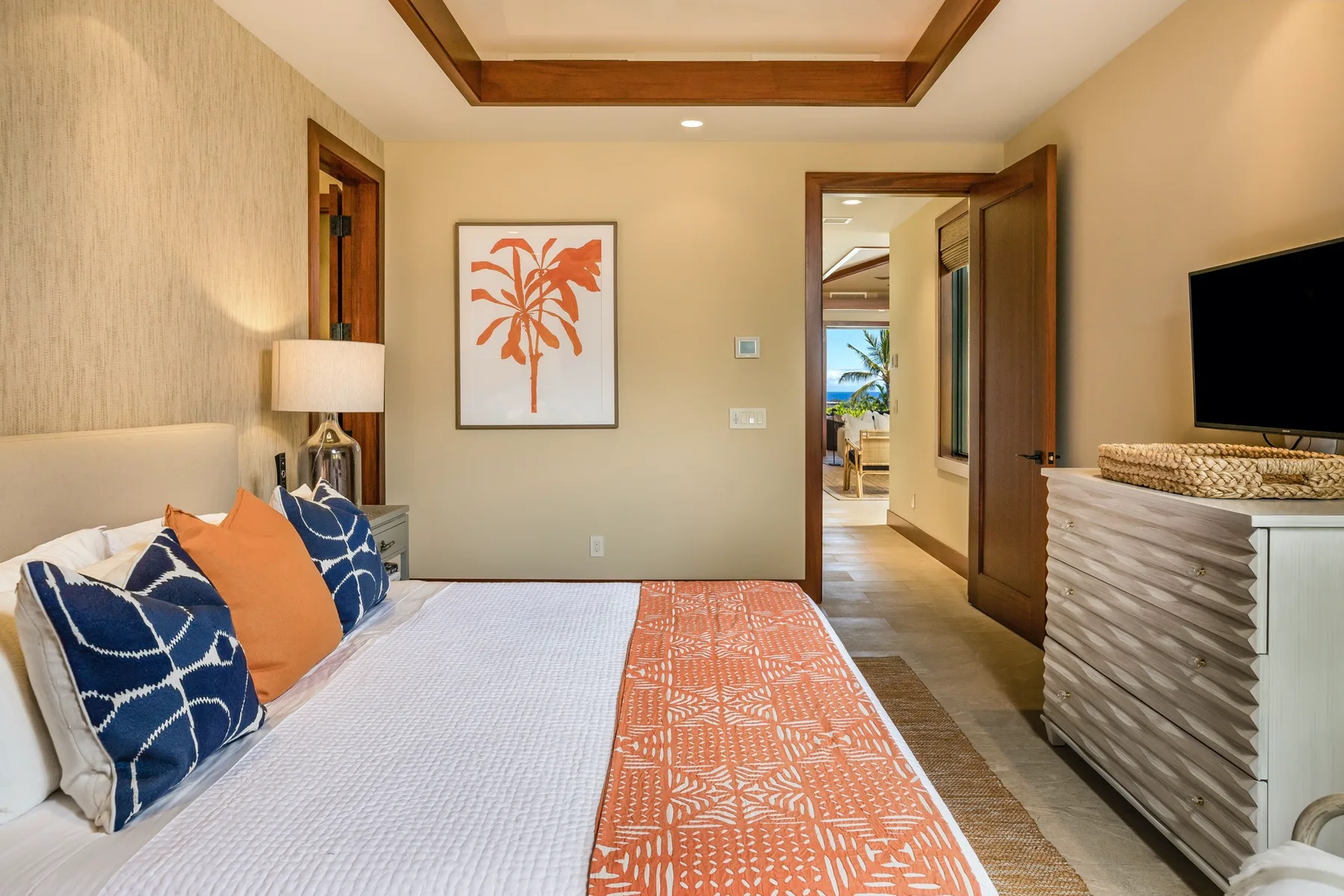 A bedroom with a bed, patterned pillows, and a framed palm print.