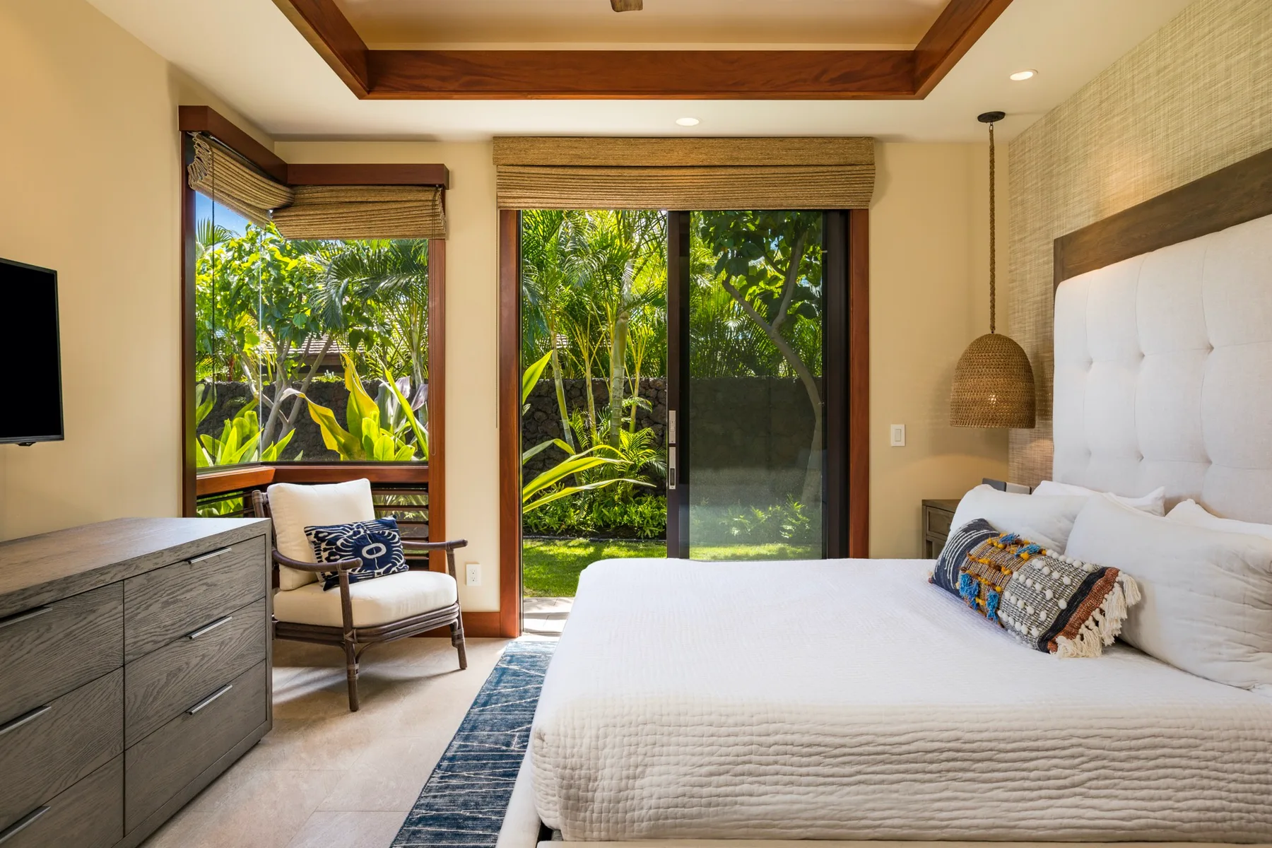 A bedroom with a large bed and sliding glass doors opening onto greenery.