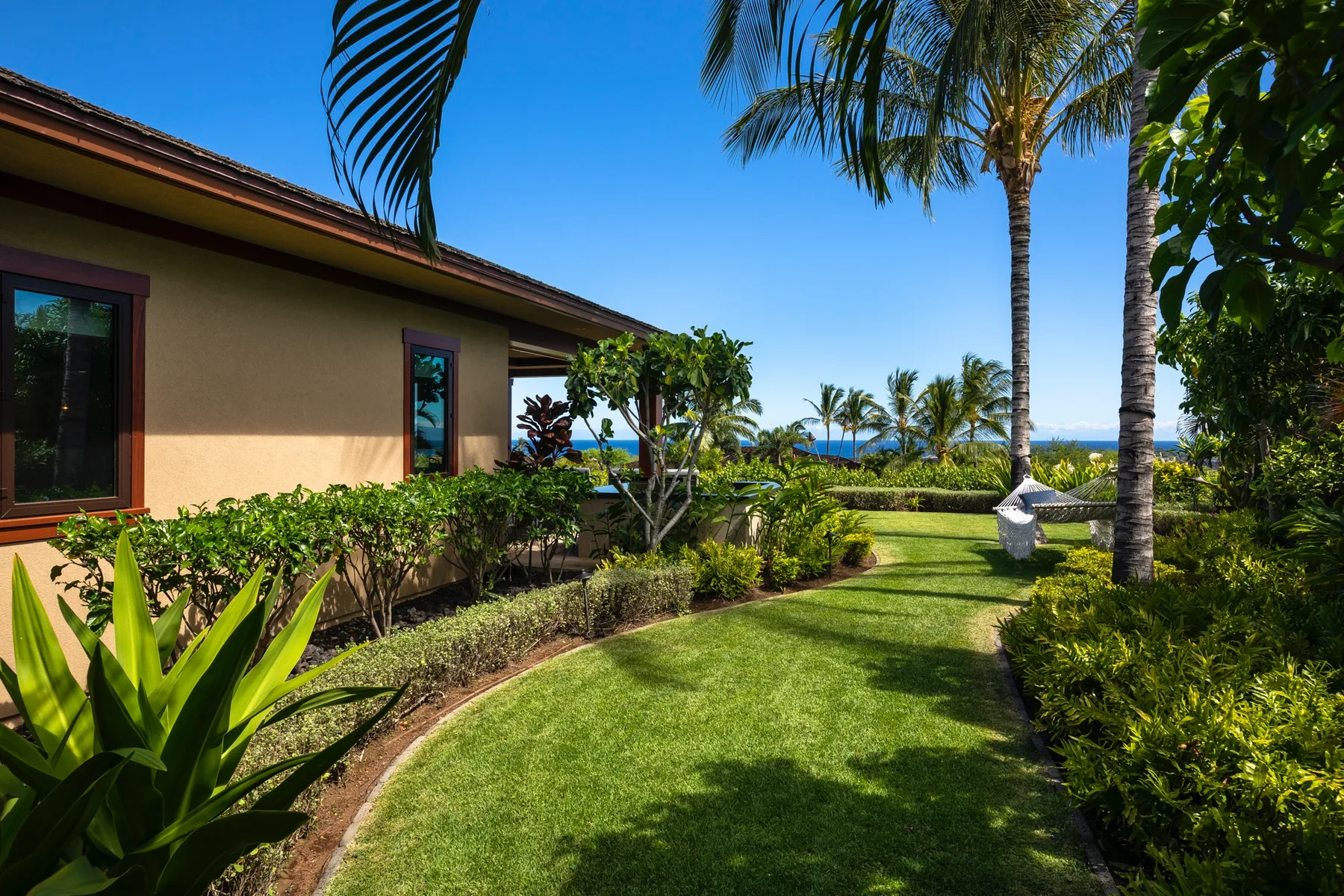 A landscaped garden beside a house, with palm trees and ocean views.