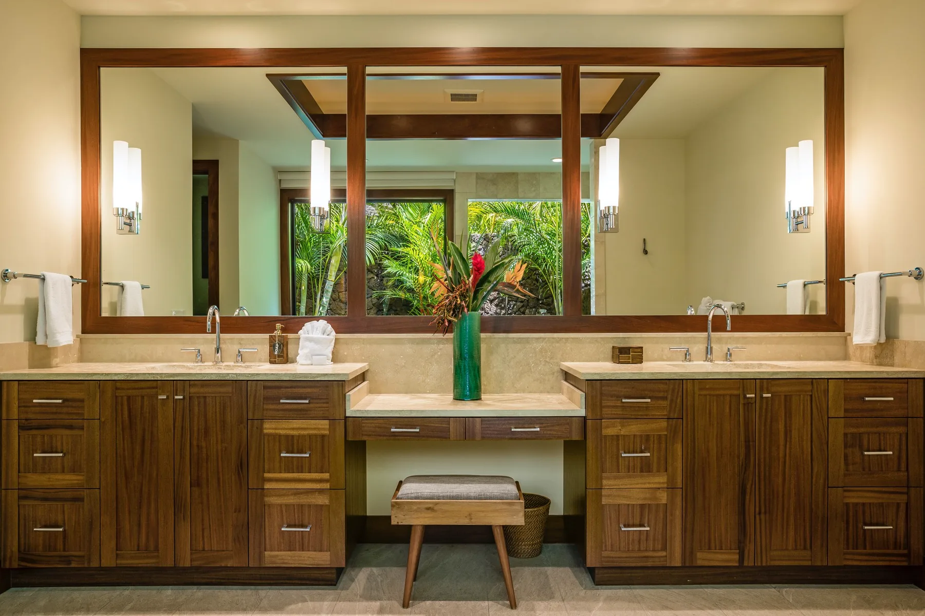 A bathroom vanity with twin sinks and a large mirror overlooking greenery.