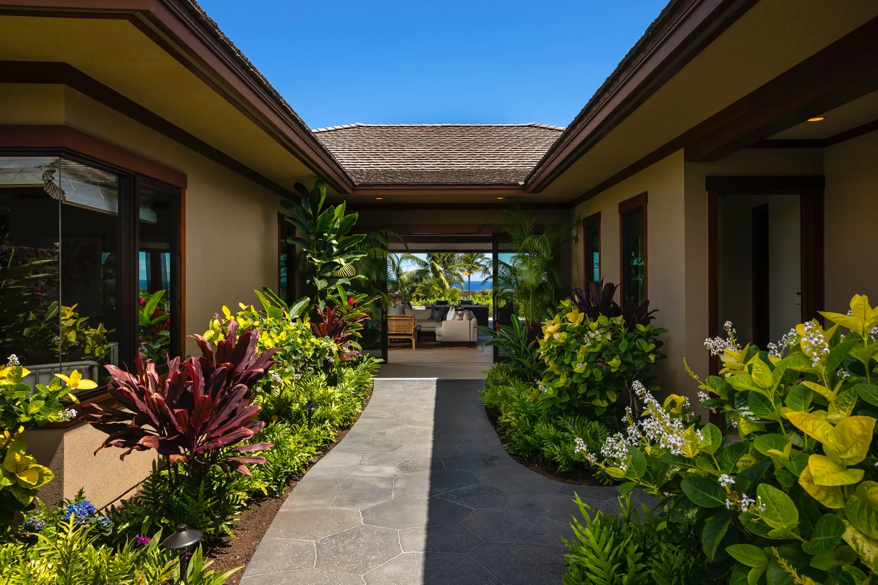 A landscaped walkway leads through a courtyard toward a covered seating area.