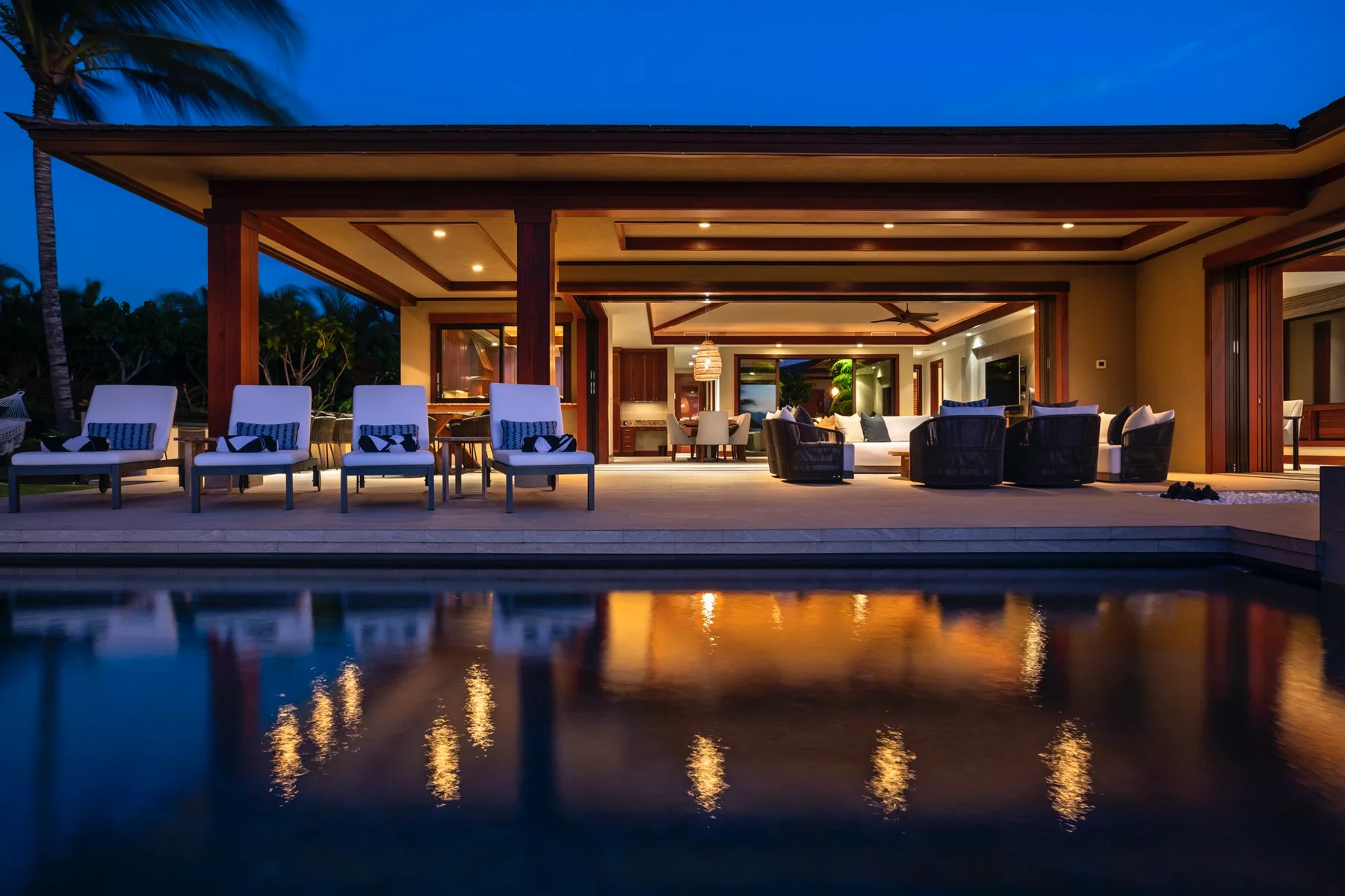 A modern outdoor living area opens onto a pool at dusk.