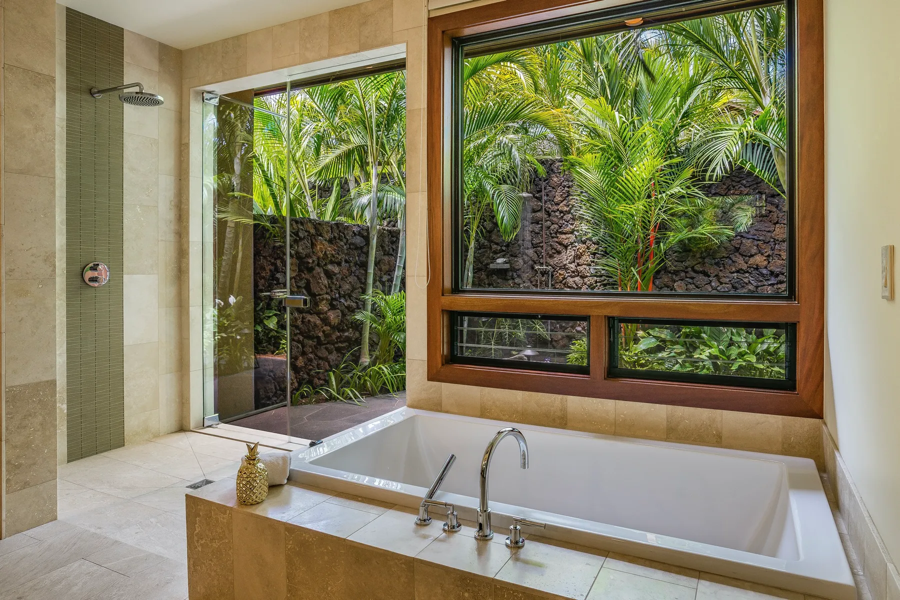 A bathroom with a bathtub beside a large window overlooking lush greenery.