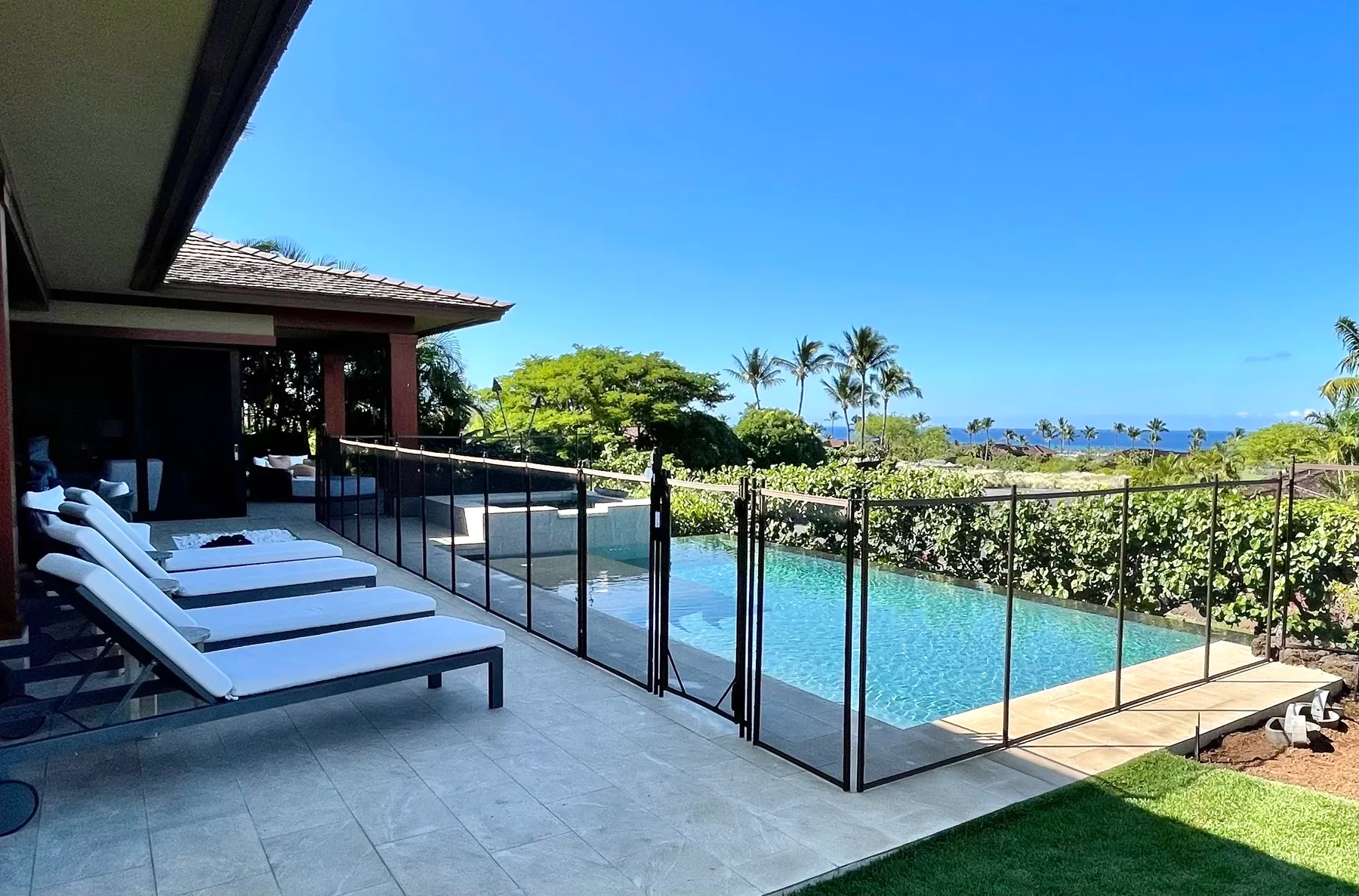 A poolside terrace with lounge seating overlooks the ocean.