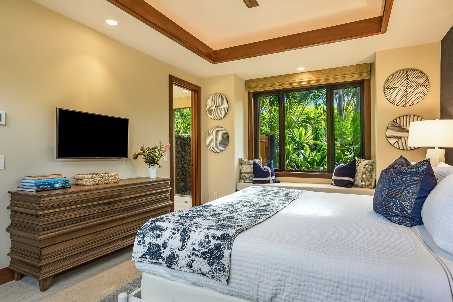 A bedroom with a large bed, a wall-mounted television, and leafy garden views.