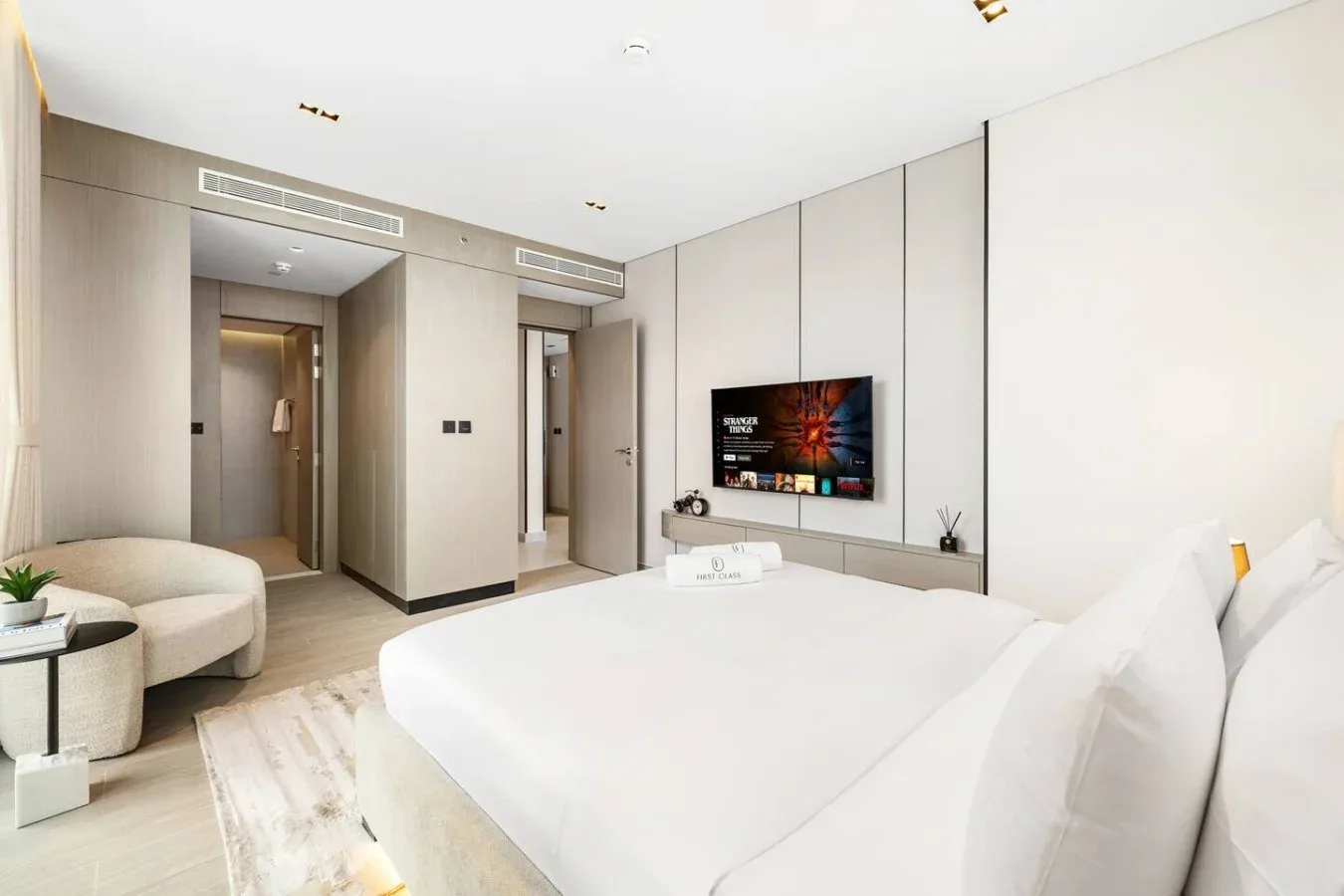 Un dormitorio luminoso con una cama grande, un televisor y una pequeña zona de estar.