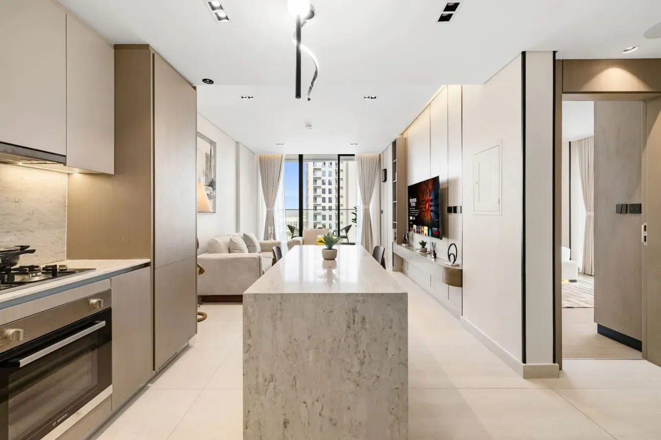 Una luminosa cocina abierta al salón, con una isla central y asientos.