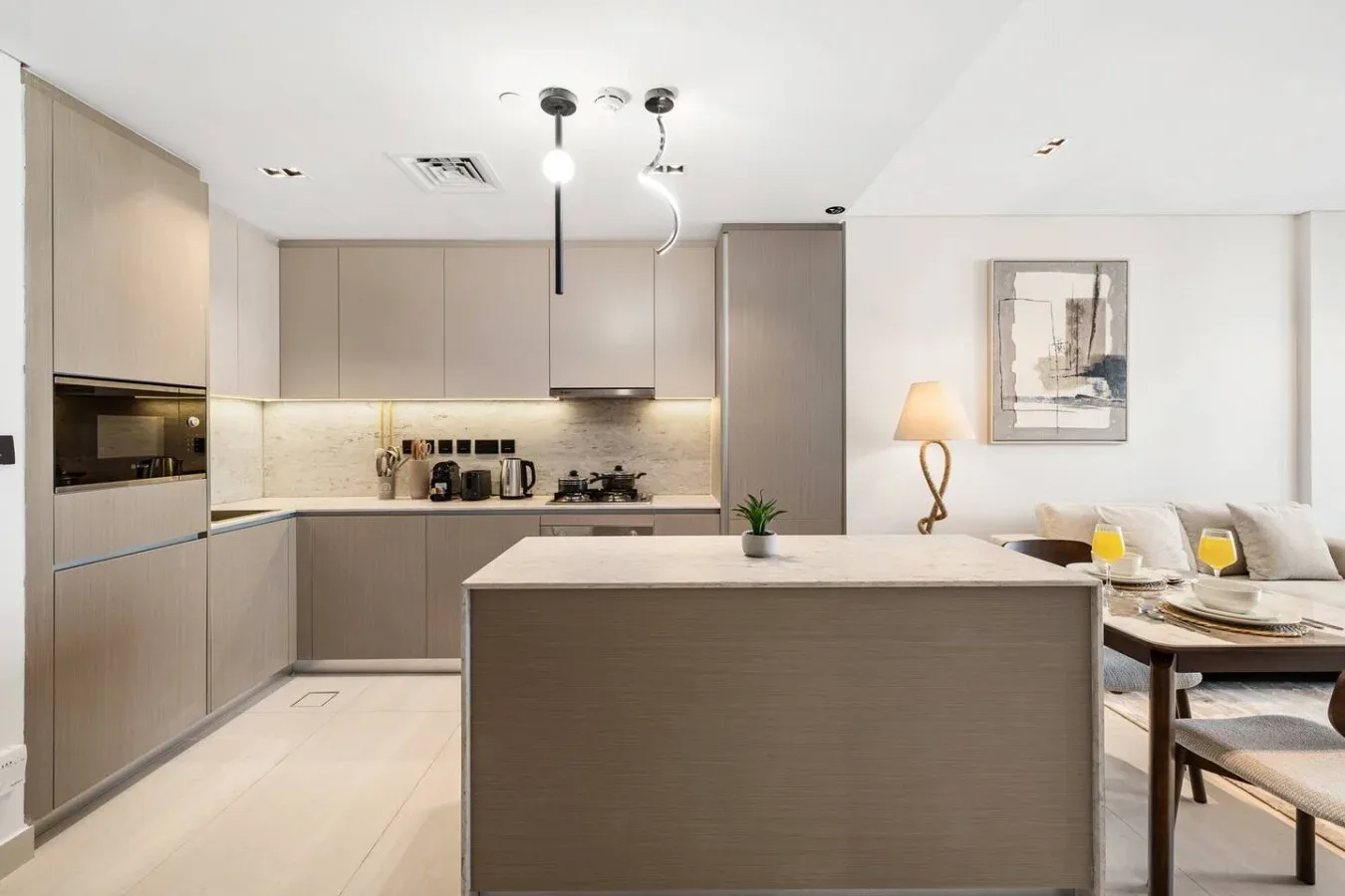 Una cocina moderna se abre a una zona de comedor y estar, con una gran isla al frente.