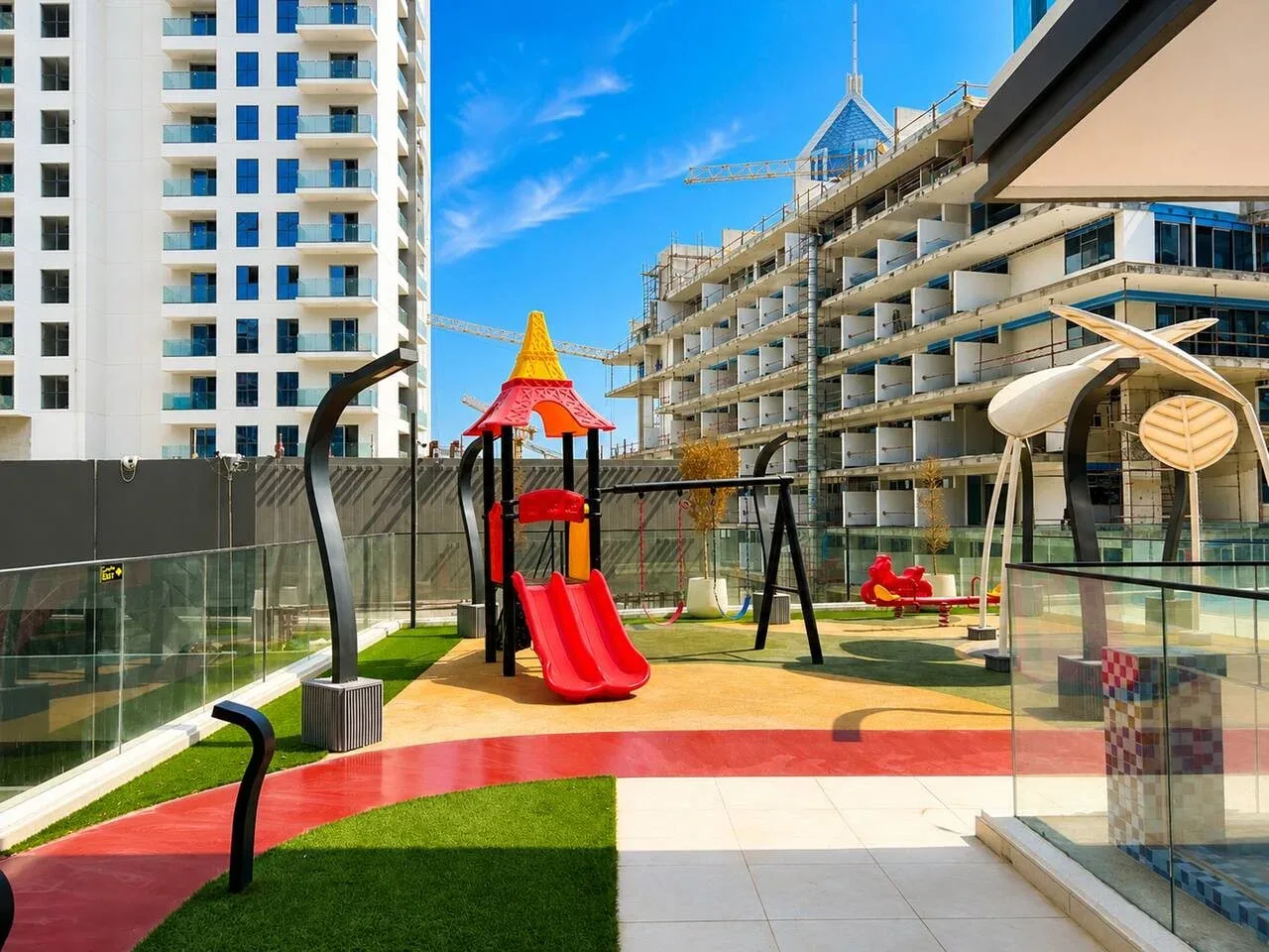 Un parque infantil al aire libre tiene un tobogán colorido y columpios entre edificios de apartamentos.