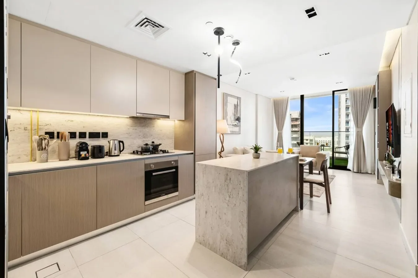 Una cocina moderna con una isla central y asientos junto a grandes ventanales.