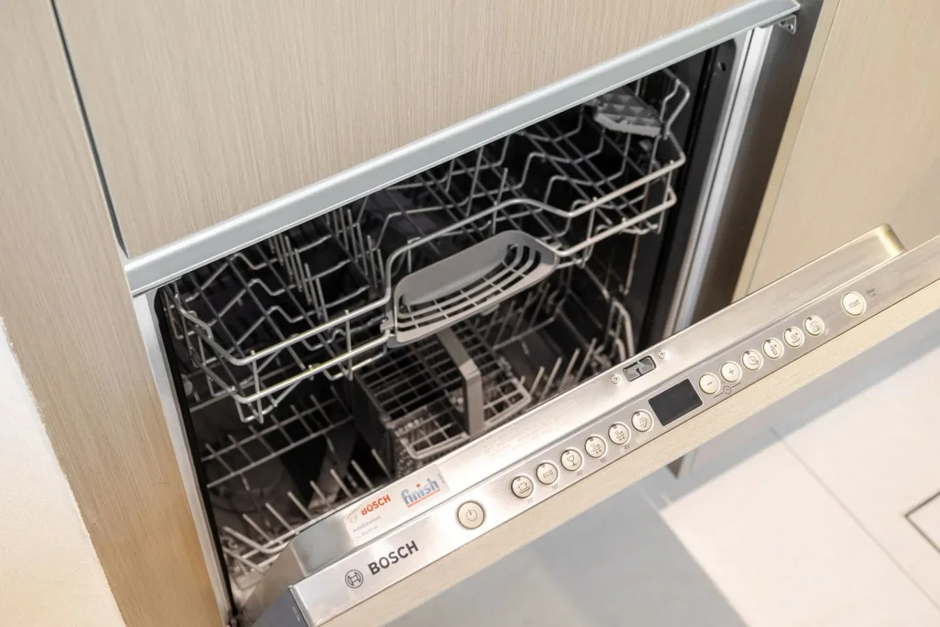 Se ve un lavavajillas abierto con las bandejas extendidas en una cocina.