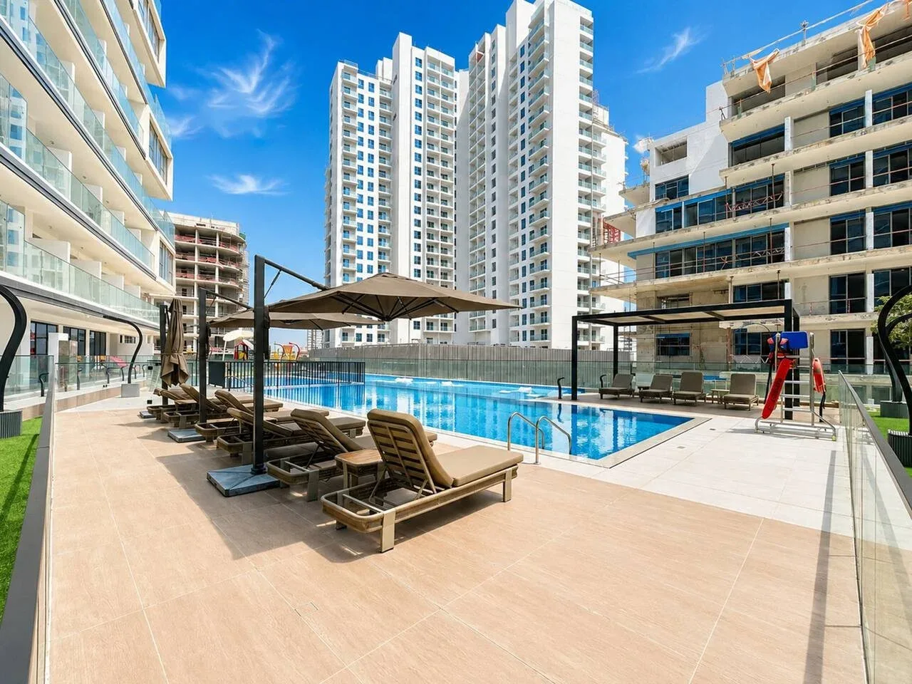 Una piscina al aire libre con asientos de descanso y edificios altos alrededor.