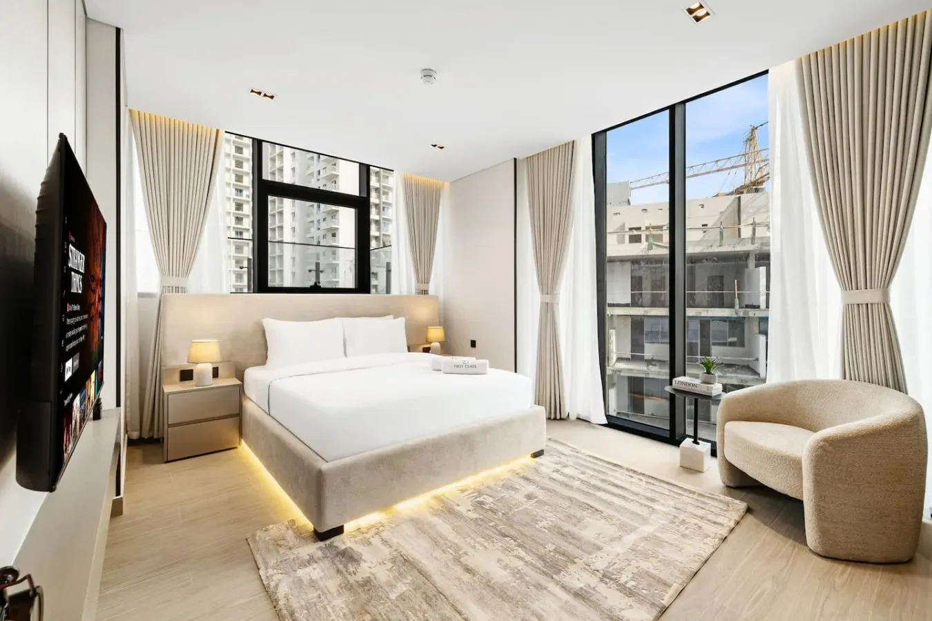 Un dormitorio luminoso con una cama grande, ventanales y un sillón.