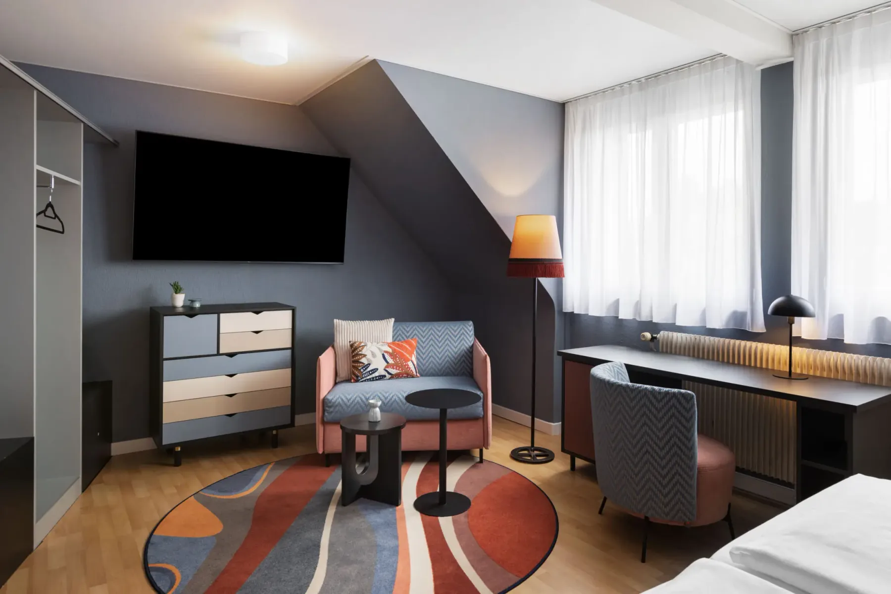 Small living area in a comfort room with sofa, desk and television.