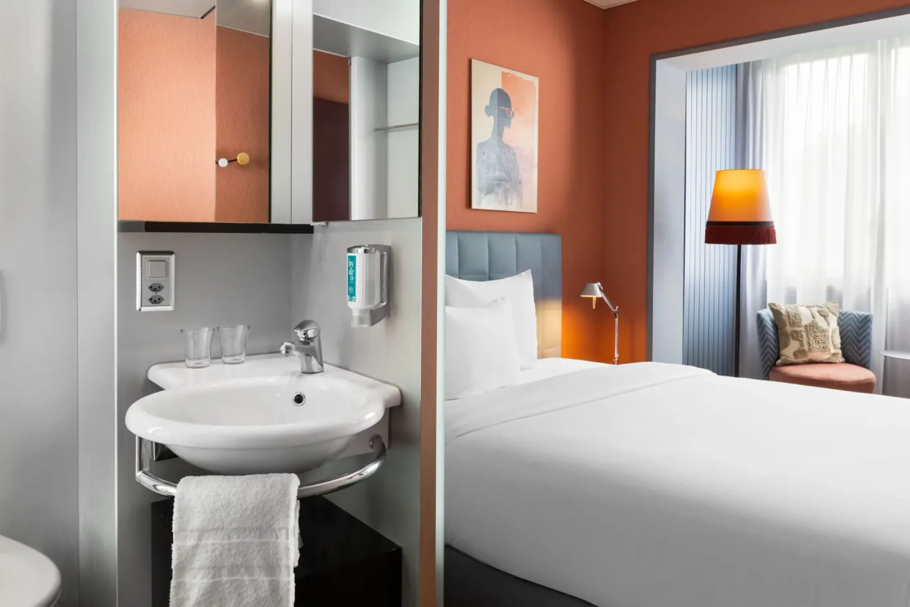 Washbasin and mirror beside the sleeping area in a business room.