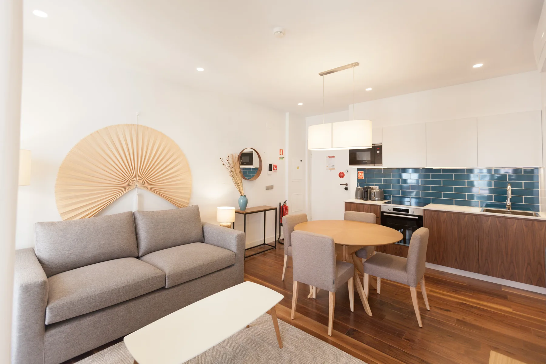 A combined living and dining area with a gray sofa and a wooden dining table.