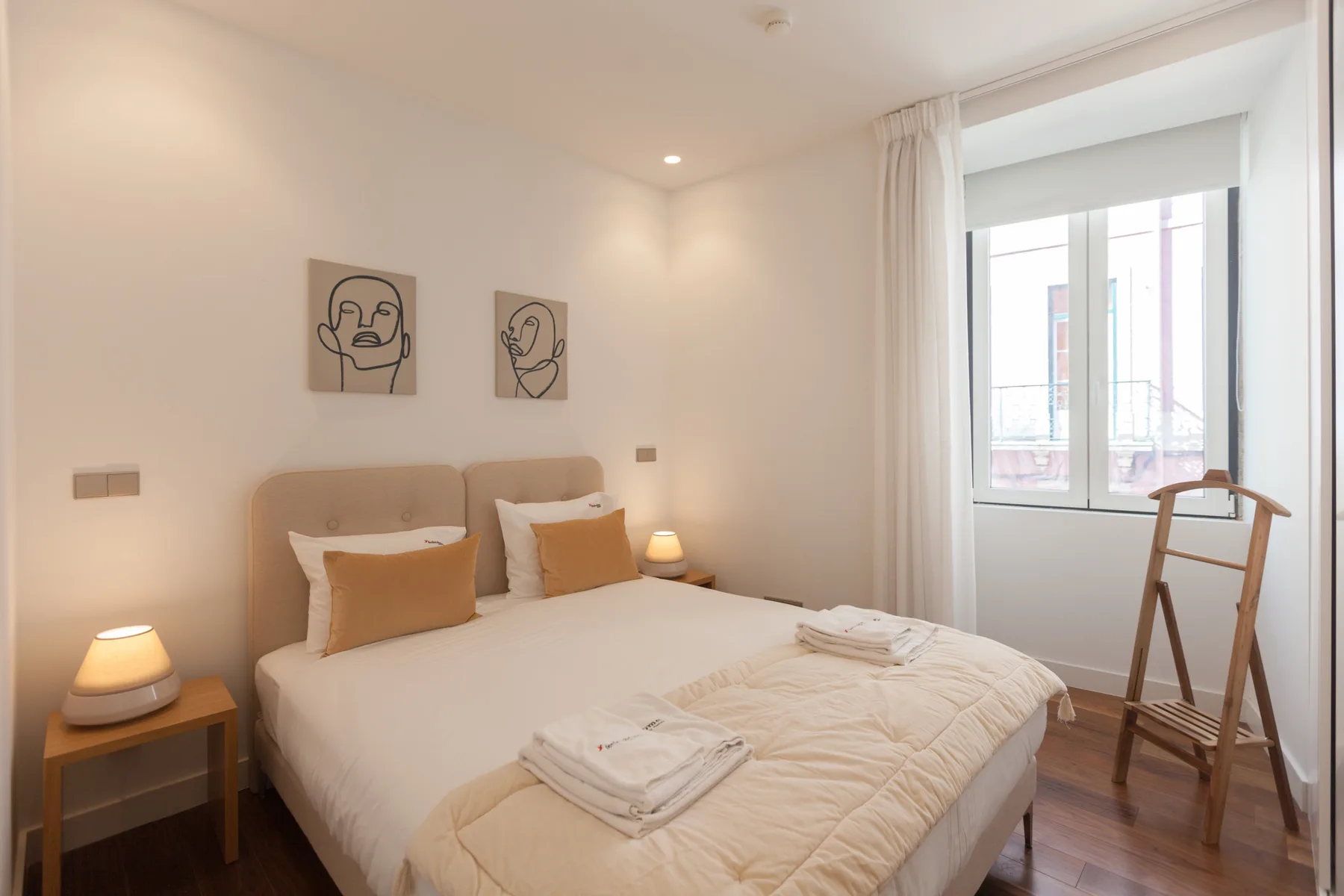 A bright bedroom with a neatly made bed beside a large window.
