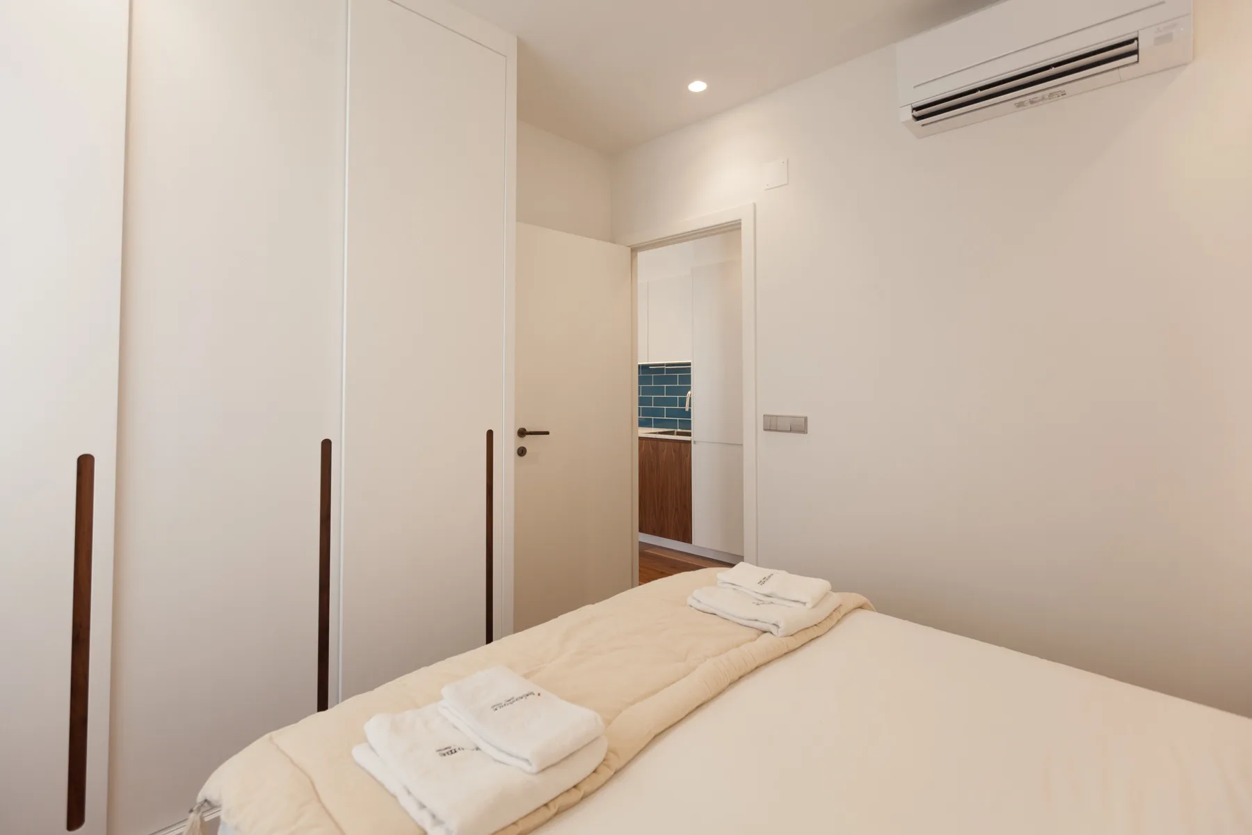 A bedroom with a neatly made bed and built-in wardrobes.