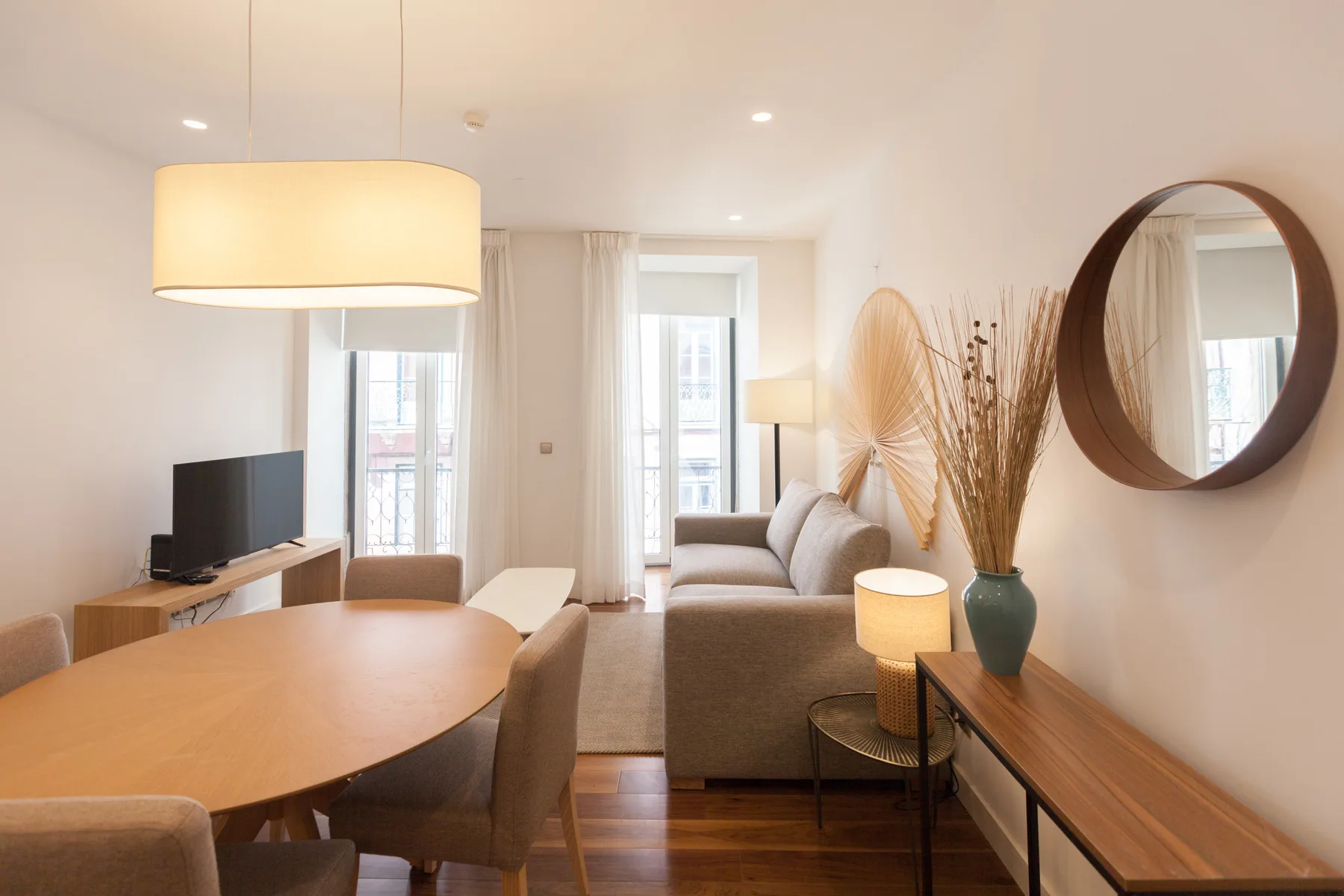 Living and dining area with a sofa, dining table, and tall windows.