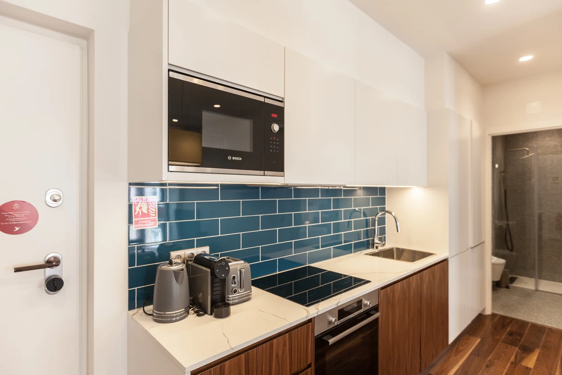 A modern kitchen with blue tile backsplash and built-in appliances.