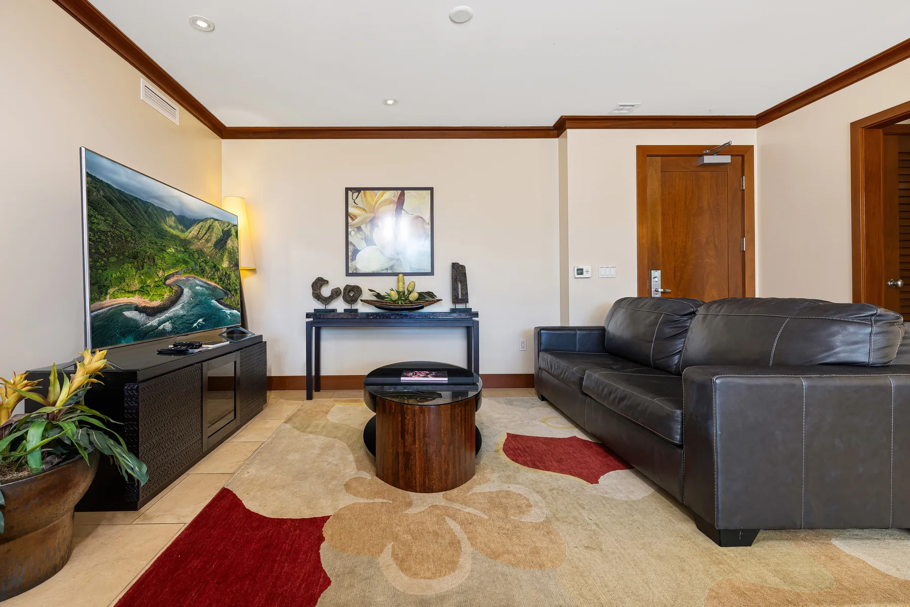 Una sala de estar con asientos oscuros, un televisor y una mesa de centro.