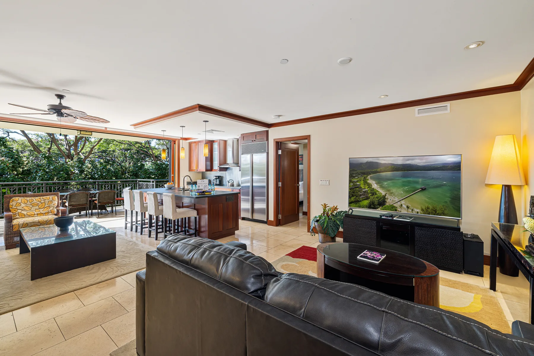 Una sala de estar con asientos, un televisor y un comedor abierto junto a las ventanas.