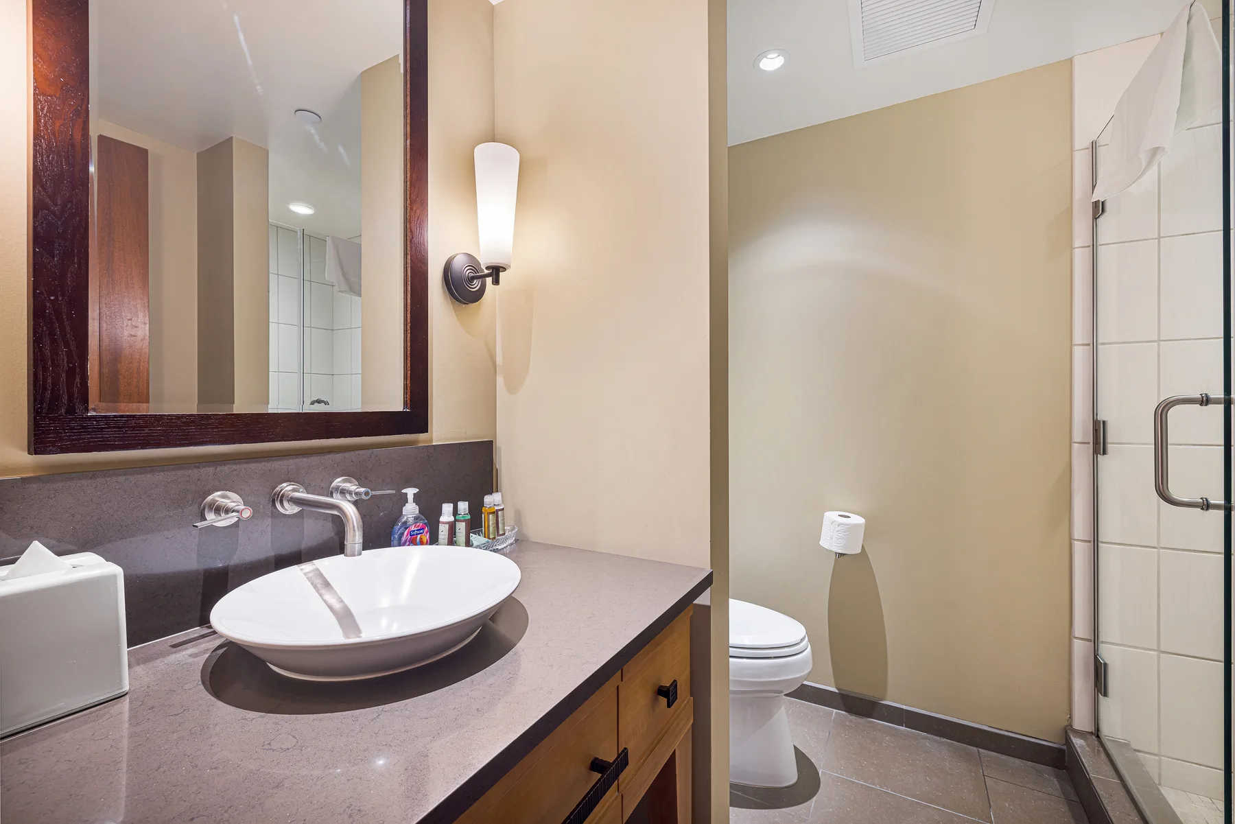 Un baño con lavabo y espejo junto al inodoro y la ducha.