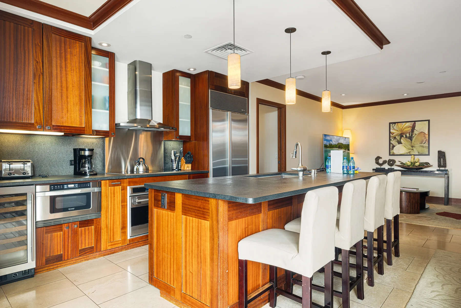 Una cocina con una isla larga, asientos blancos y gabinetes de madera.