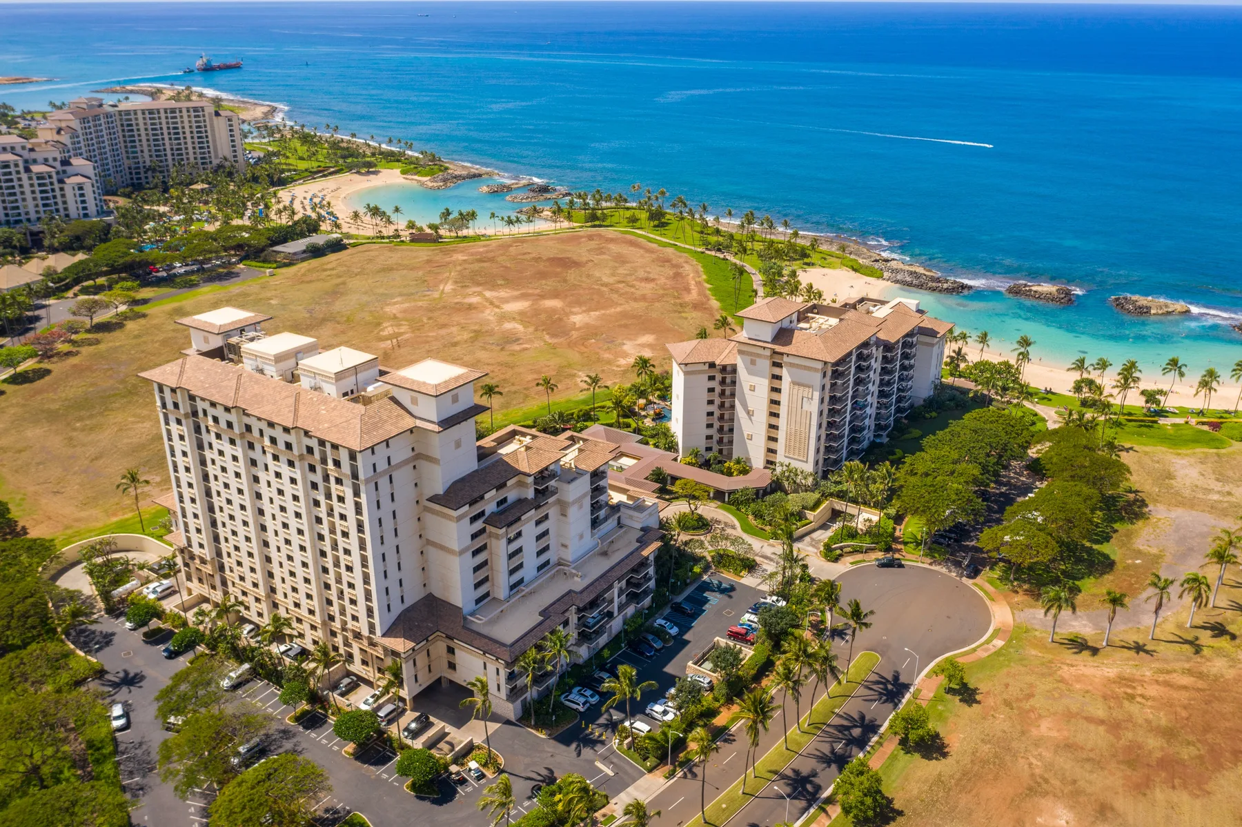Vista aérea de edificios junto a la playa, jardines y el océano azul.