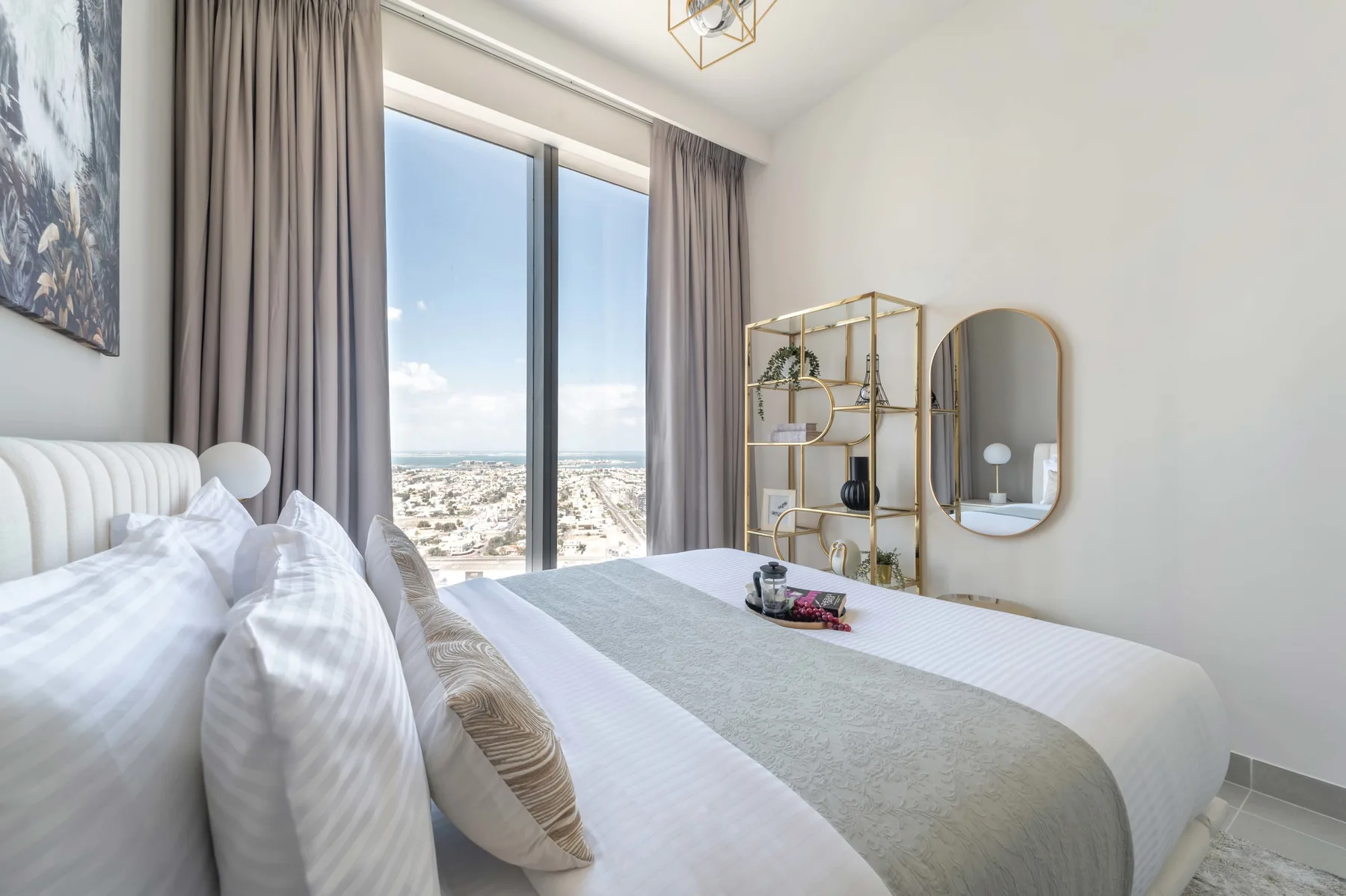 Un dormitorio luminoso con una cama grande y cortinas altas frente a la ciudad.