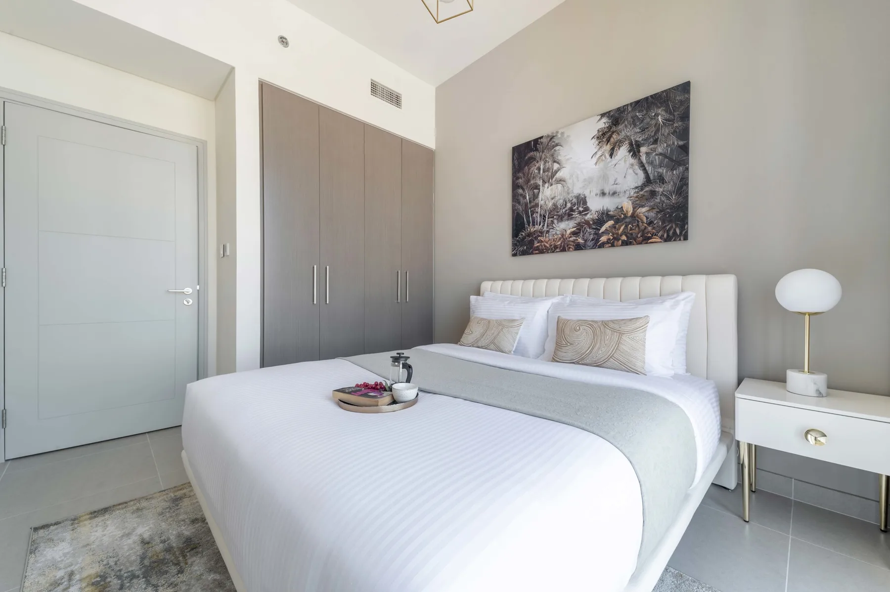 Un dormitorio luminoso con una cama bien tendida y un armario.