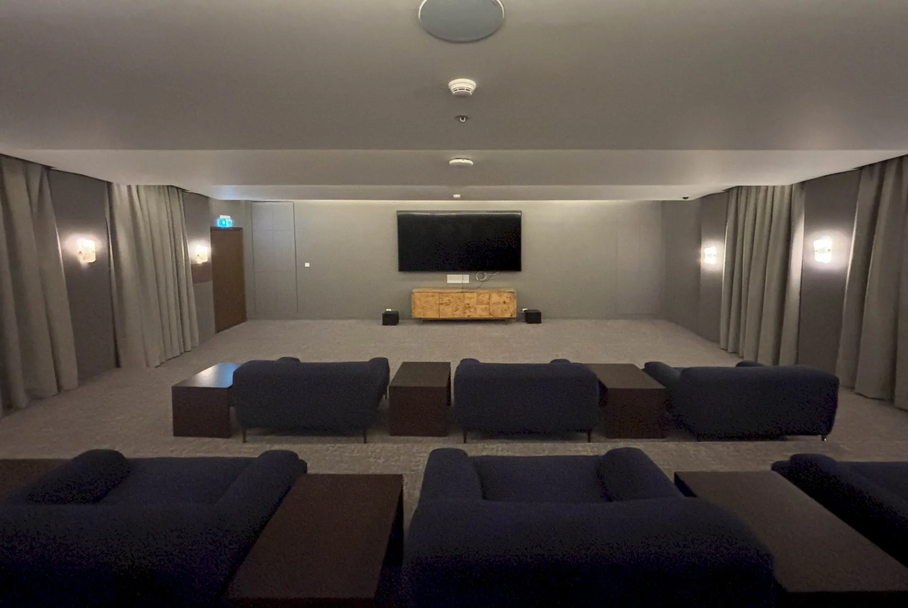 Una sala de medios con filas de asientos frente a un televisor.