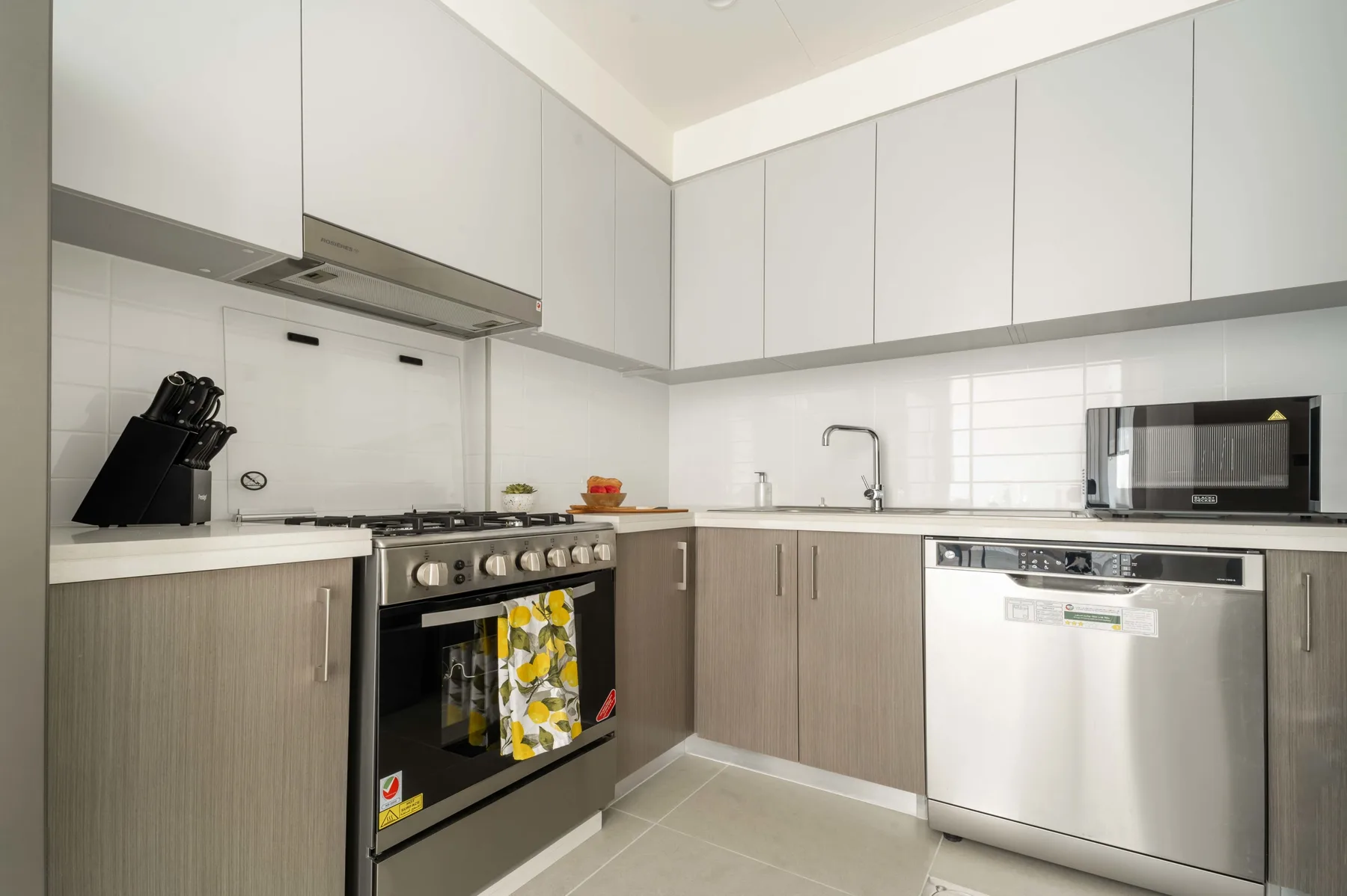 Una cocina moderna con gabinetes claros, una estufa y un fregadero.