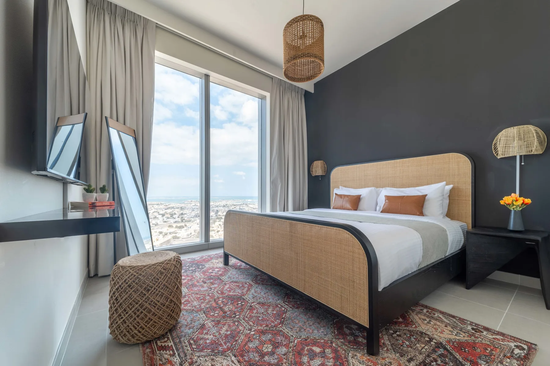 Un dormitorio con una cama grande, una alfombra estampada y ventanas con vistas al mar.