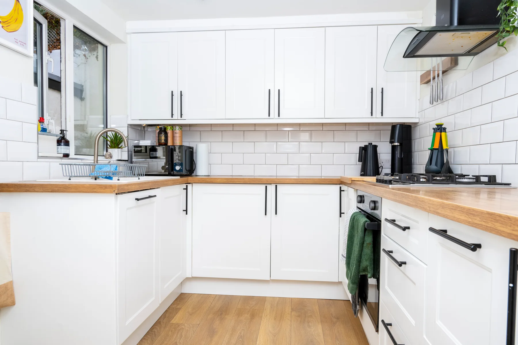 A bright kitchen with white cabinets and wooden countertops.