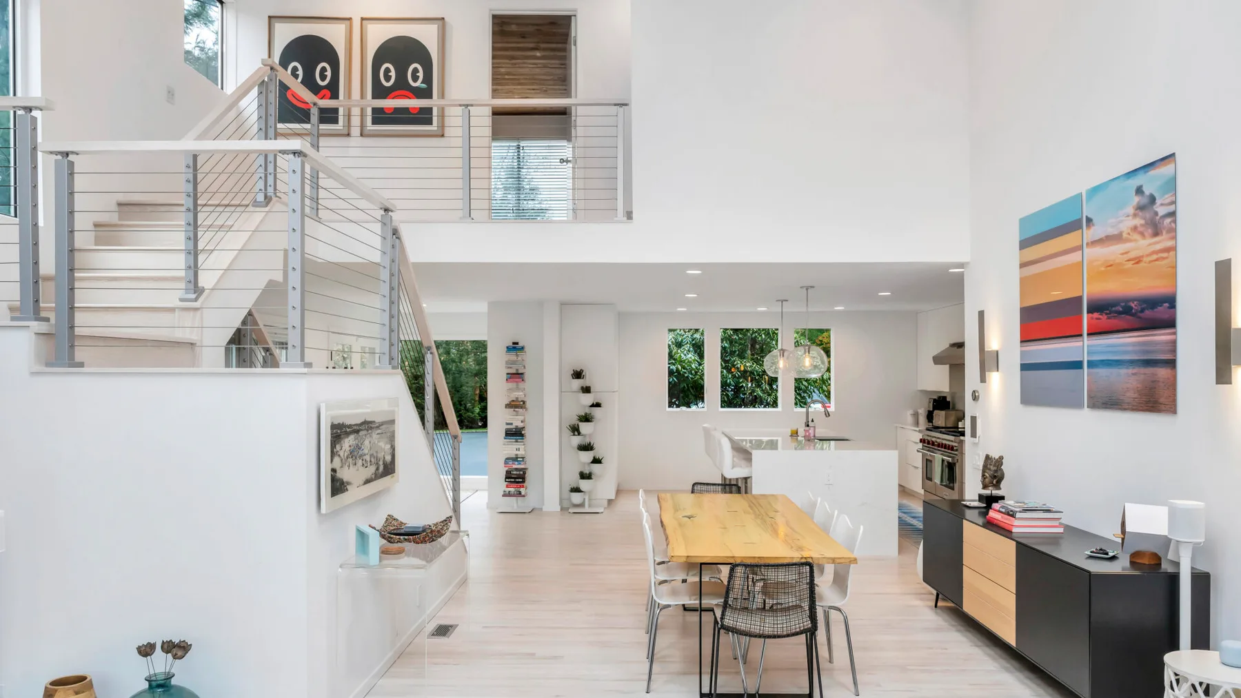 Una luminosa sala-comedor de concepto abierto con mesa de madera y escalera.
