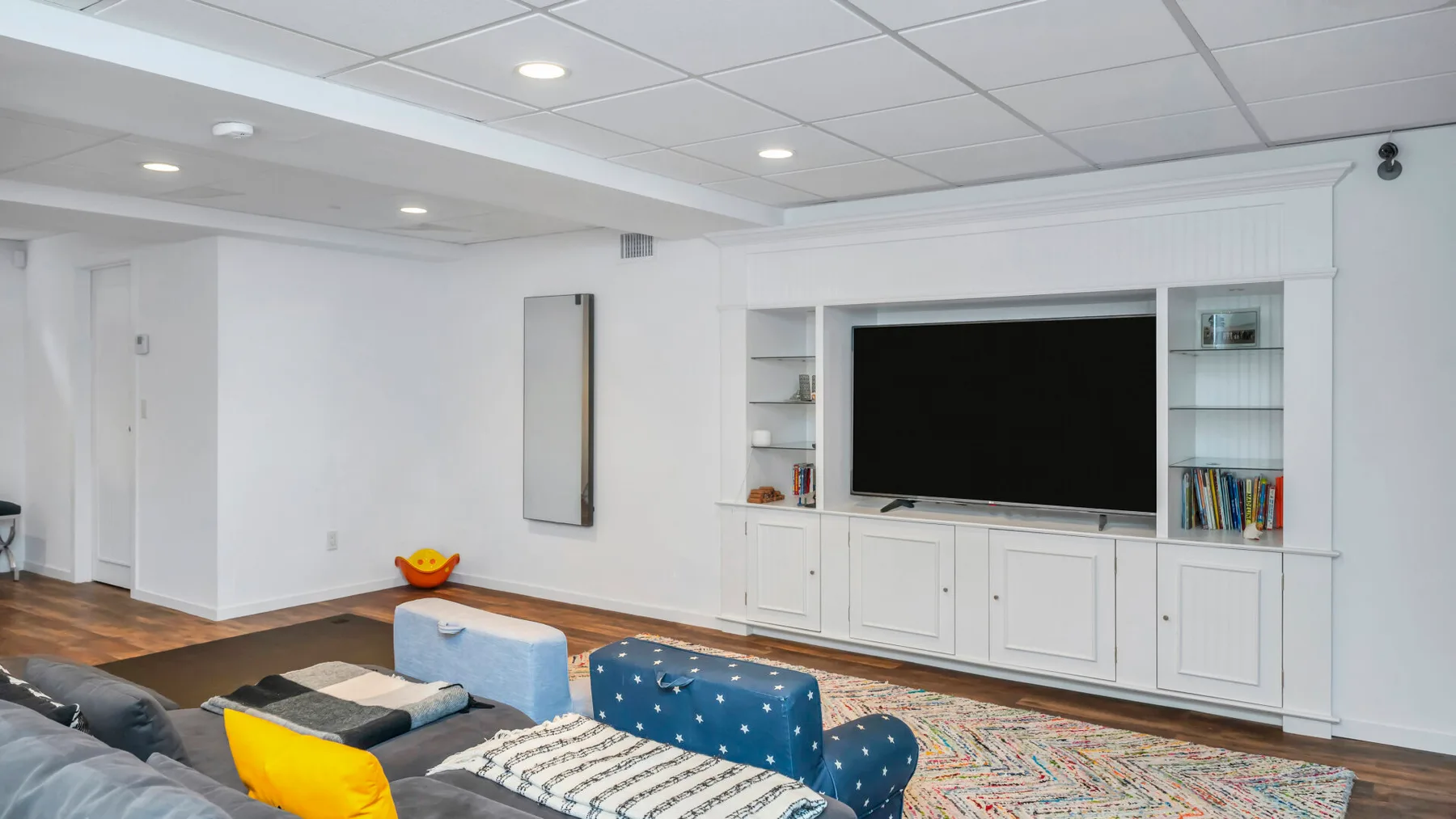 Una sala luminosa con un televisor grande integrado en un mueble empotrado.