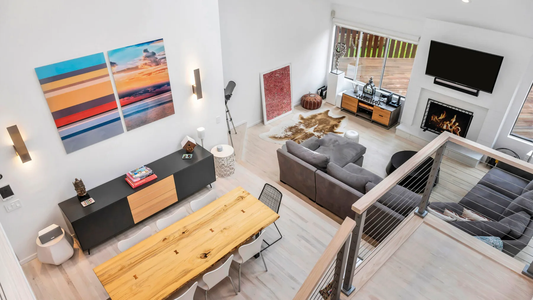 Una sala luminosa con asientos, un televisor y arte colorido en la pared.