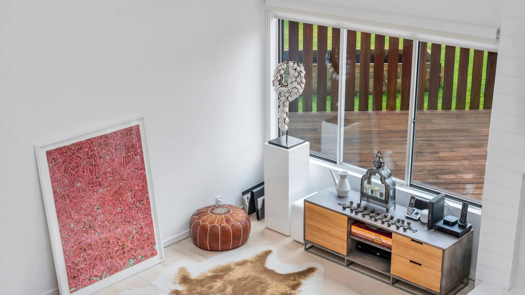 Una sala luminosa con un mueble bajo junto a grandes ventanas con vistas a una terraza.