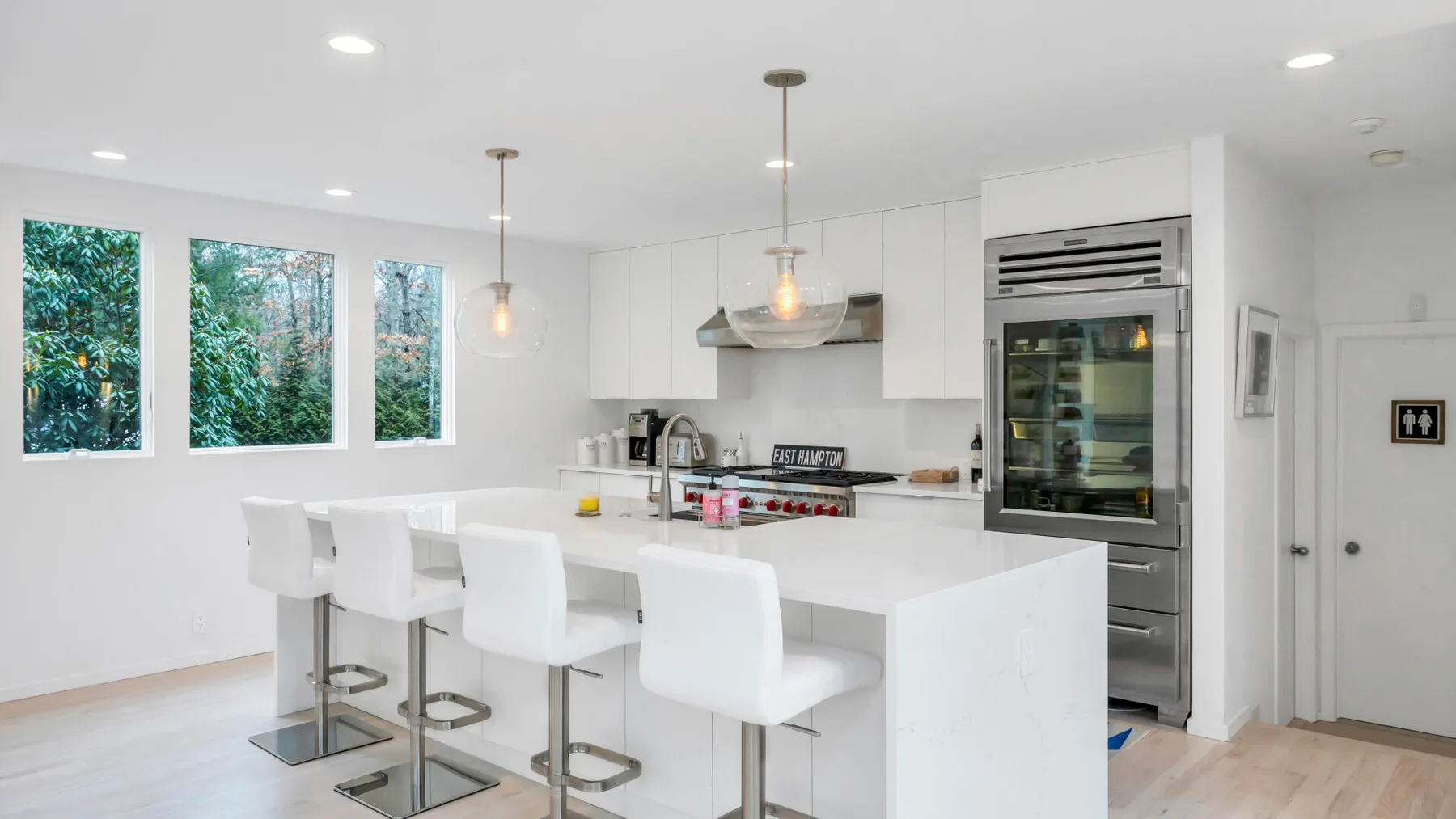 Una cocina moderna y luminosa con una isla grande y asientos blancos.