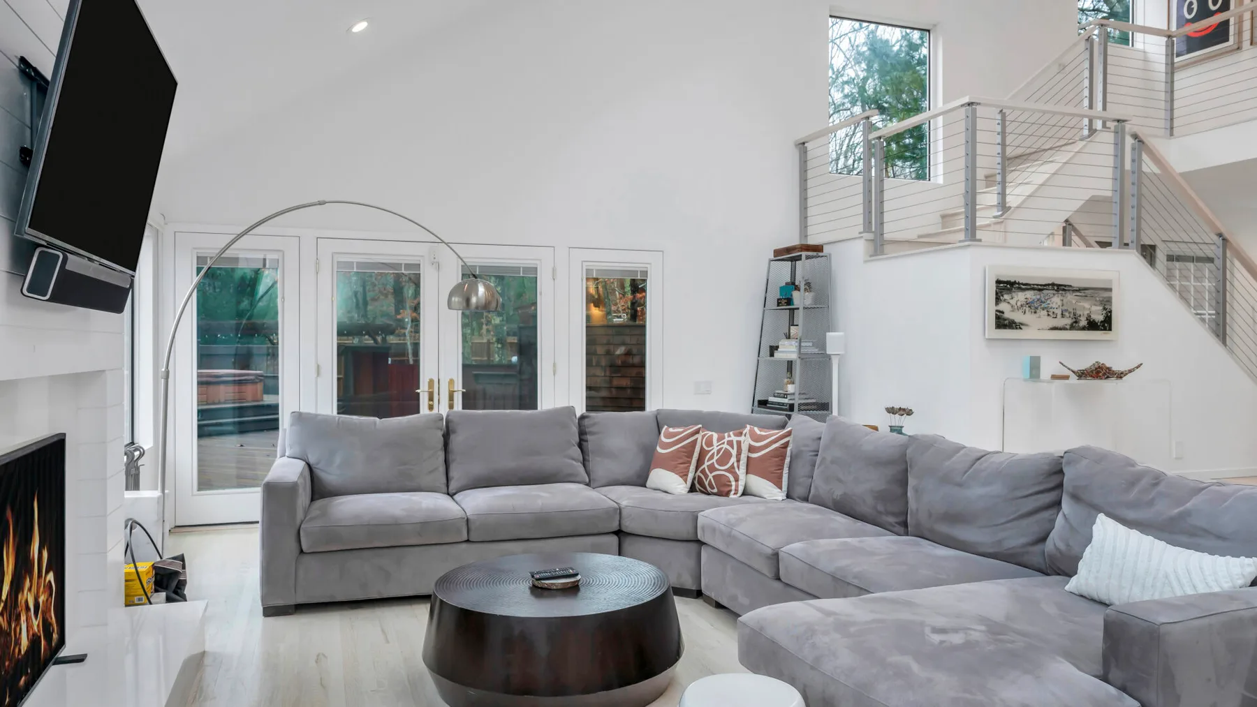 Una sala luminosa con un sofá seccional gris y una mesa de centro redonda.