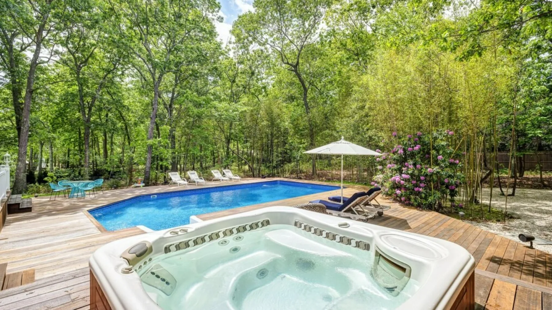 Una piscina y una bañera de hidromasaje al aire libre junto a una terraza de madera.