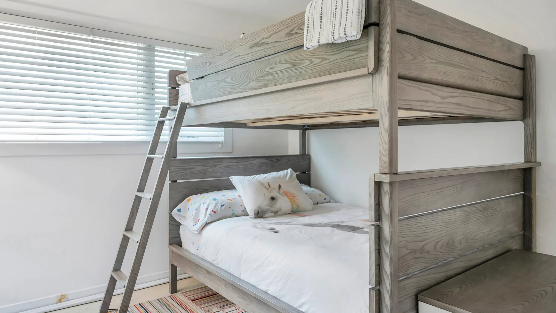 Un dormitorio con una litera de madera y un gato descansando en la cama inferior.